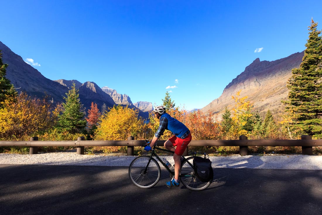 A cyclist takes in the fall view in Glacier National Park, Montana on the Going to the Sun Road.